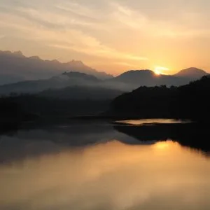 Lever de soleil, reflet sombre des montagnes sur le lac, la surface de l'eau est limpide et dorée